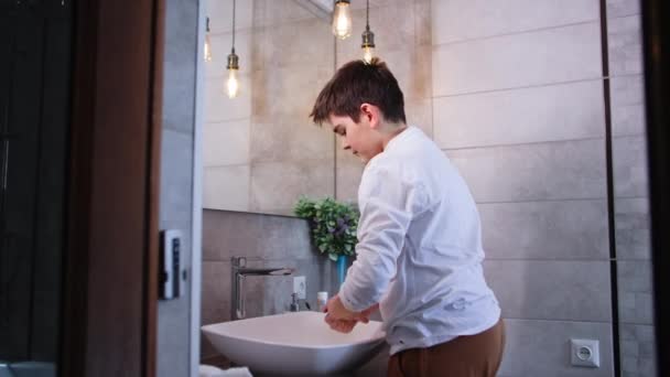 個人的な衛生 かわいいティーンエイジャーは液体石鹸を使用して手を洗い バスルームのシンクの近くに立っている間泡から洗います — ストック動画