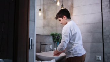 Sabah prosedürleri, tatlı çocuk banyo lavabosunun yanında dururken yüzünü suyla yıkar.