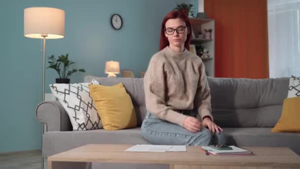 共同アパートの借金 メガネを持つ若い女性は 部屋の自宅に座っているアカウントサービスのための大きなアカウントのために電話で呪う — ストック動画