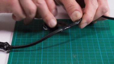 Elektrikli ev aletleri tamiri, erkek elektrikçi kabloları tamir ediyor ve yakın plan elektrik bandını çıkarıyor.