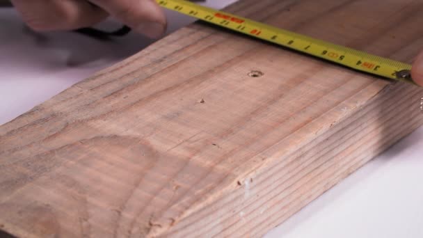 Stolarz Przy Użyciu Taśmy Konstrukcyjnej Mierzy Drewnianą Deskę Cięcia Piły — Wideo stockowe