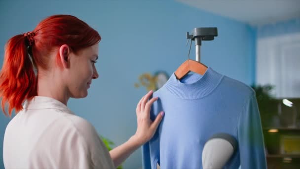Wanita Muda Menggunakan Uap Panas Menyetrika Sweater Pada Gantungan Rumah — Stok Video