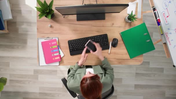 コンピュータで働く若い女性は 電話で話し オフィスのテーブルに座っている間 彼女の手に反ストレスのおもちゃを抱えています トップビュー — ストック動画
