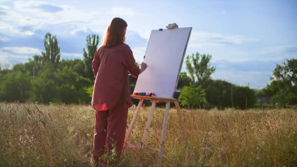 用画笔和丙烯酸颜料在户外画一幅画的有创意的女画家 — 图库视频影像