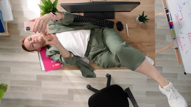午休时间 女办公室职员躺在办公室的桌面上 在电话上通过视频交谈 — 图库视频影像