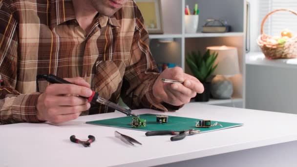 男用电工坐在房间的桌子边 用焊接工具焊接微电路 — 图库视频影像