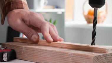 Mobilyacı, ev aletleri kullanan bir adam mobilya toplarken tahta tahtada delik açıyor.