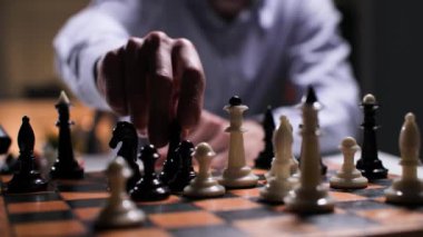 Strateji ve planlama konsepti, genç adam satranç tahtasında bir taşla hamle yapıyor, yakın plan.