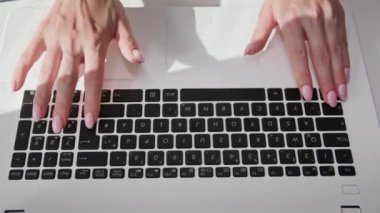 Dizüstü bilgisayarda yazı yazan bir kadın. Masada oturuyor. Yakın plan.