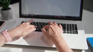 Kadın ofis çalışanı dizüstü bilgisayarda çalışıyor ve klavyede daktilo kullanıyor.