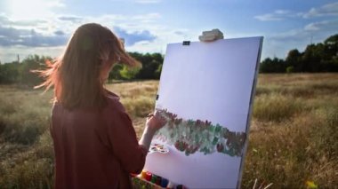 Yaratıcı hobi, fırça ve resim yardımıyla kadın sanatçı açık hava sehpası kullanarak tuvale resim çizer.