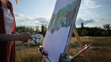 Yaratıcı hobi, fırça ve resim yardımıyla kadın sanatçı açık hava sehpası kullanarak tuvale resim çizer.