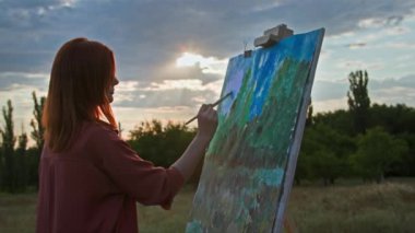 Yaratıcı hobi, boya ve fırça kullanan kadın sanatçı güneş ışınlarının ve gün batımının resmini çiziyor.