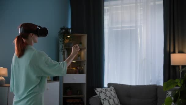 站在舒适的房间里 戴着虚拟现实眼镜的年轻女性在视频通话中与朋友交谈 — 图库视频影像