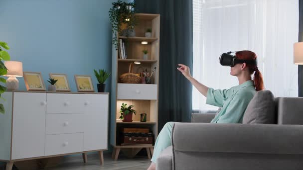现代技术 坐在虚拟现实眼镜上的女人坐在房间沙发上 看着网页和网站 — 图库视频影像