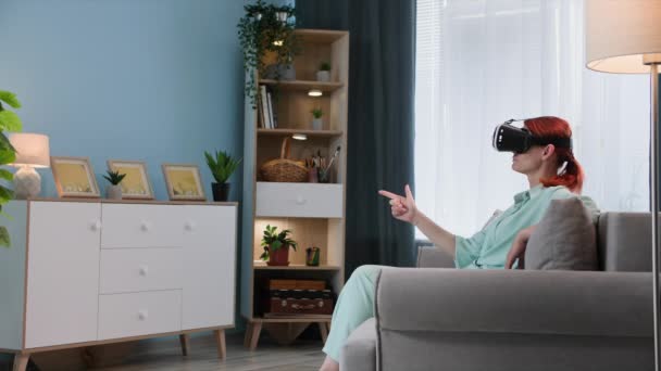 虚拟现实中 一位戴面纱的年轻女性坐在沙发上 正在使用现代技术上网 — 图库视频影像