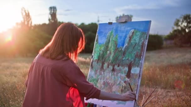 在阳光的映衬下 一个有才华的年轻女子 带着绘画和刷子 在公园里用画架画出一幅有创意的图画 — 图库视频影像