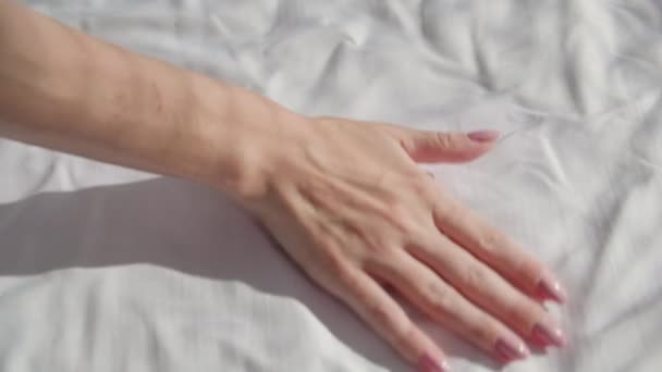 朝のルーチン 若い女性は太陽のベッドにきれいな白いシートをストローク 手のクローズアップ — ストック動画