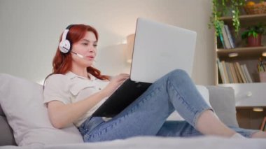 Serbest iş, genç güzel bir kadın çağrı merkezinde çalışıyor ve odada kanepede yatarken kulaklık ve dizüstü bilgisayar kullanarak müşteriyle iletişim kuruyor.