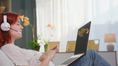 Çağrı merkezi, kulaklıklı kadın laptopla konuşuyor ve yatakta yatıyor.