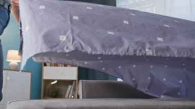 Sabah rutini, ev hanımı yatak odasını hazırlıyor, yakın plan.