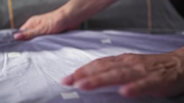 Genç bir kadın uyuduktan sonra yatağını temizlerken elleriyle yatak örtüleri sarıyor.