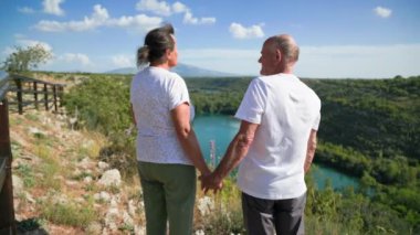 Emeklilik seyahati, sevgi dolu yaşlı bir çift güzel manzaranın tadını çıkarıyor ve sıcak bir günde birlikte seyahat ederken el ele tutuşuyorlar.
