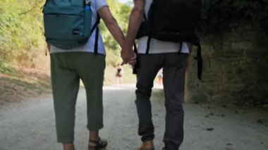 Emekli geziler, birlikte parkta yürürken sırt çantalı neşeli yaşlı adam ve kadın.