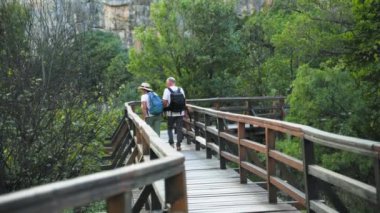 Aktif emekliler, mutlu yaşlı adam ve kadın sıcak bir günde köprüde el ele yürüyorlar.