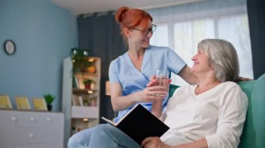 Yaşlı, genç bayan çalışanı desteklemek Yaşlı bir kadına bir bardak temiz içme suyu getirmek