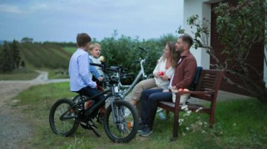 Mutlu erkek çocuklar ebeveynleriyle elma yerken şehir dışında bisiklet sürerken eğleniyorlar.