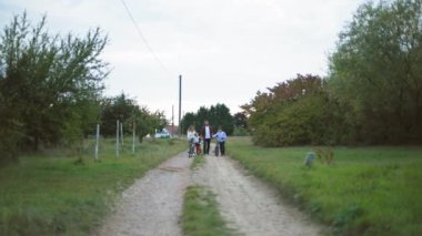 Aile yürüyüşü, mutlu erkek ve kadın ve erkek çocukları kırsal yolda yürürken eğleniyorlar.