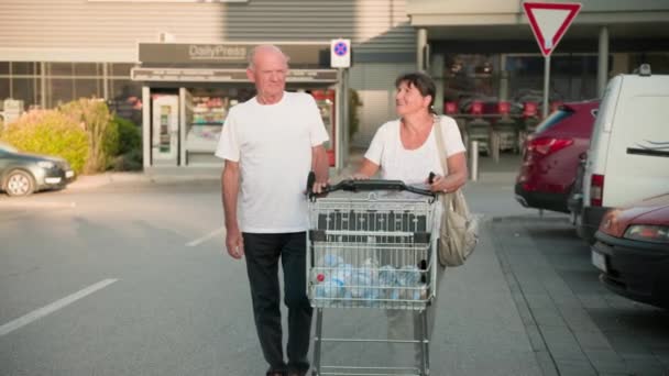 Elderly Couple Cart Bottles Water Walks Street Warm Day — Stock Video