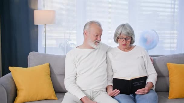 Заботясь Пенсионерах Пожилая Супружеская Пара Наслаждается Отдыхом Чтением Книги Сидя — стоковое видео