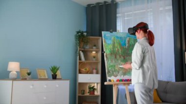 Modern sanat, yetenekli kadın ressam evde viar gözlüklerle dikilirken tuvalle resim çizer.