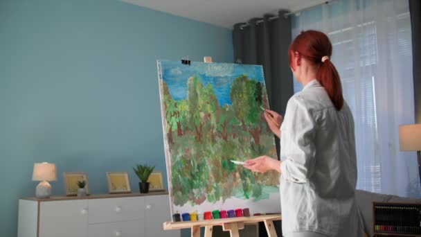 在家庭娱乐中 有才华的女画家在舒适的房间里用画架在画布上画画和刷画图 — 图库视频影像