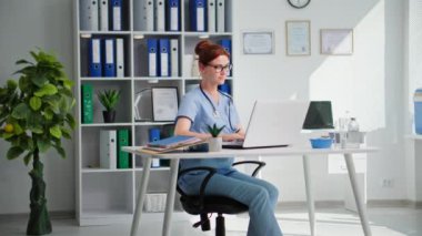 Sağlık hizmetleri, güzel kadın doktor. Tıp ofisinde otururken bilgisayar başında çalışıyor.