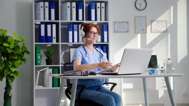 Joven Doctora Consulta Pacientes Usando Auriculares Video Comunicación Computadora Mientras — Vídeos de Stock