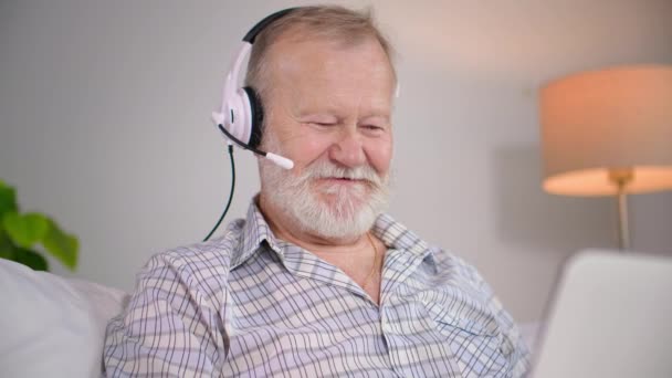 Zdalna Komunikacja Starszy Mężczyzna Słuchawkami Rozmawia Przez Wideokonferencję Laptopie Relaksując — Wideo stockowe