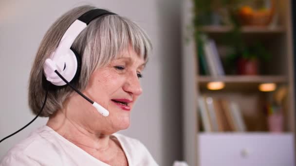 Χαρούμενη Ηλικιωμένη Συνταξιούχος Μικρόφωνο Και Ακουστικά Χρησιμοποιεί Βιντεοκλήση Στο Laptop — Αρχείο Βίντεο