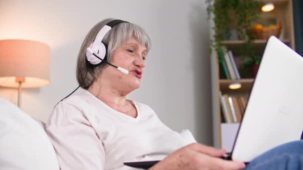 Alegre Pensionista Femenina Con Auriculares Utiliza Tecnología Moderna Para Comunicarse — Vídeo de stock