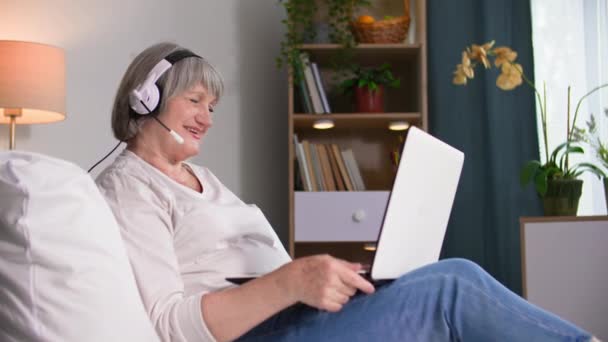 Hermosa Anciana Hablando Través Videollamada Con Auricular Ordenador Portátil Mientras — Vídeos de Stock