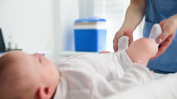 子供の健康 女性の医師は病院で小さい患者を受け取っている間骨盤のテーブルの赤ん坊を検査します — ストック動画