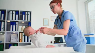 Çocuk sağlığı ve genç bayan doktor, muayenede küçük çocuğu muayene eder.