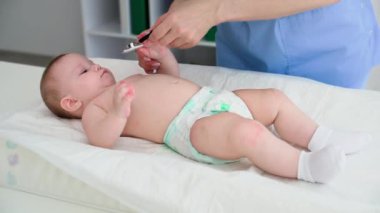 Bebek sağlığı ve genç bir bayan doktor, ofiste masaları değiştirirken yapılan tıbbi muayene sırasında küçük bir çocuğu fonendoskopla inceliyor.
