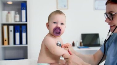 Doktorun muayenehanesinde emzik taşıyan küçük bir çocuğun portresi.