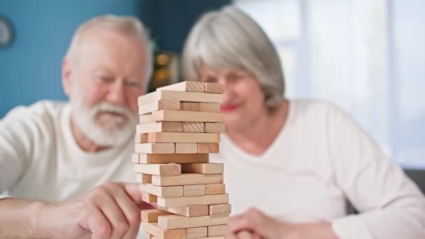 快乐的老人和心甘情愿的女人玩棋盘游戏 用木块和特写建造一座塔 玩得很开心 — 图库视频影像