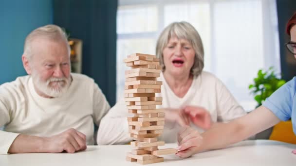 Счастливые Пенсионеры Играют Настольные Игры Вместе Социальным Работником Сидя Столом — стоковое видео