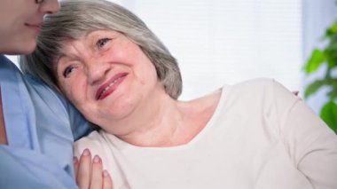 Emeklilere destek, kanepede otururken kadın sosyal hizmet görevlisiyle konuşan yaşlı bir kadın.
