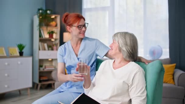 Cuidado Ancianos Mujer Joven Uniforme Médico Trae Vaso Agua Limpia — Vídeos de Stock